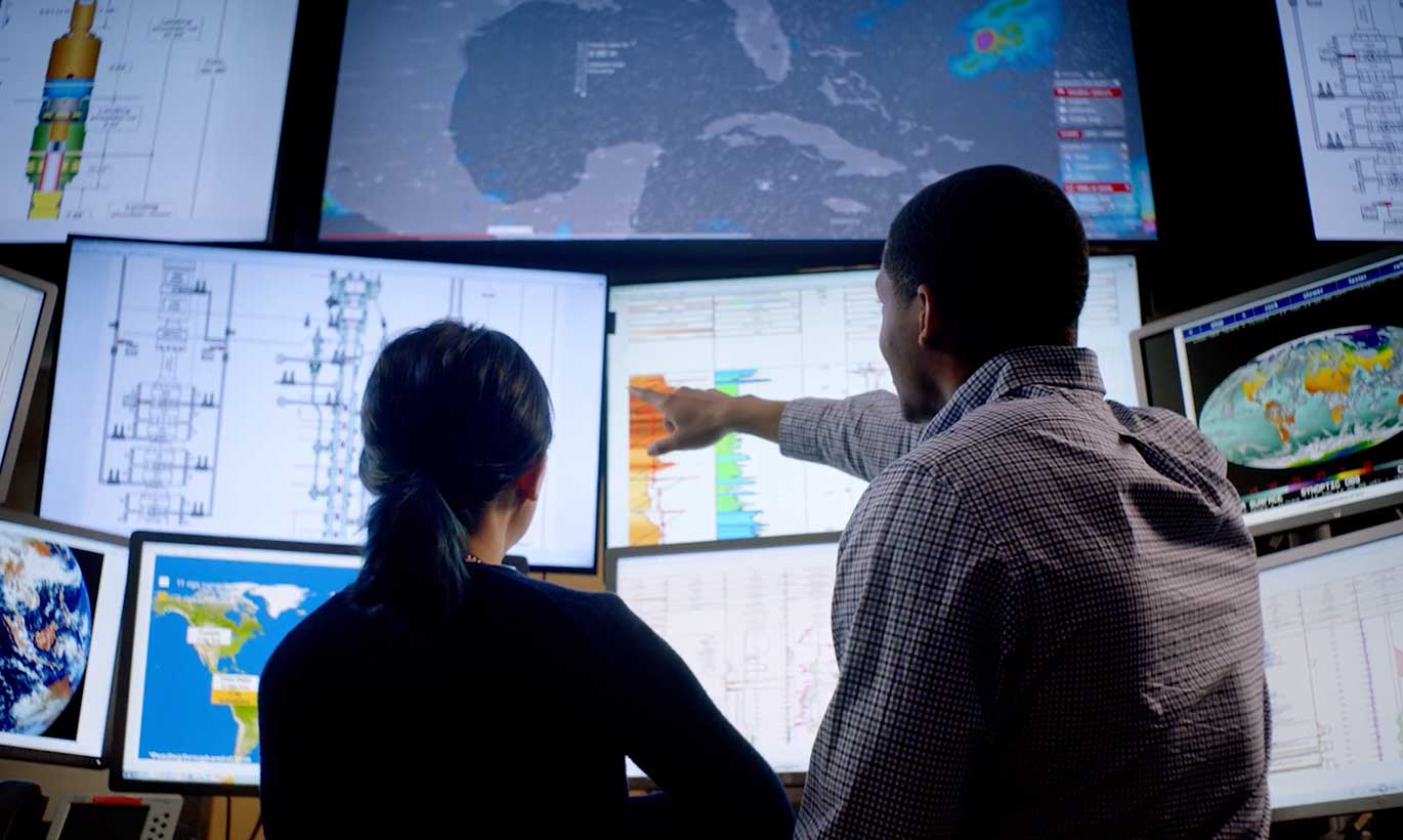 A man and woman point out important data and statistics on energy graphs and maps in Houston, Texas